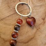 Porte clé cœur rouge composé d'un coeur en jaspe rouge, de pierres d'obsidienne acajou, de sardonyx, de pietersite. Un porte clé pour être bien ancré, protégé - L'alvéole des minéraux