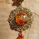 Ce pendentif cornaline et ambre est composé d'une orgonite contenant de l'ambre et de la cornaline et d'une perle en pierre de cornaline